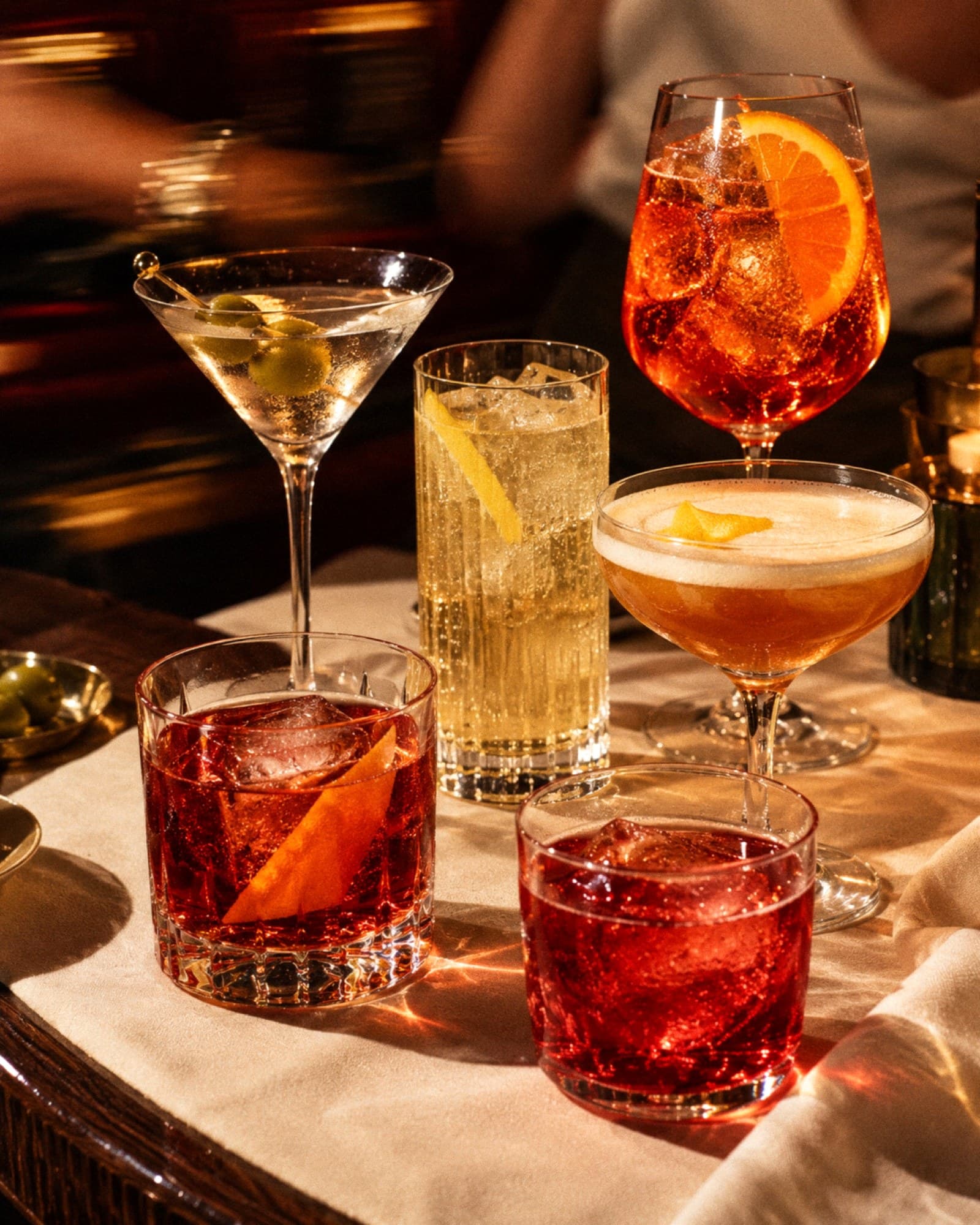 A negroni, martini, spritz, highball and sours on a candlelit bar table